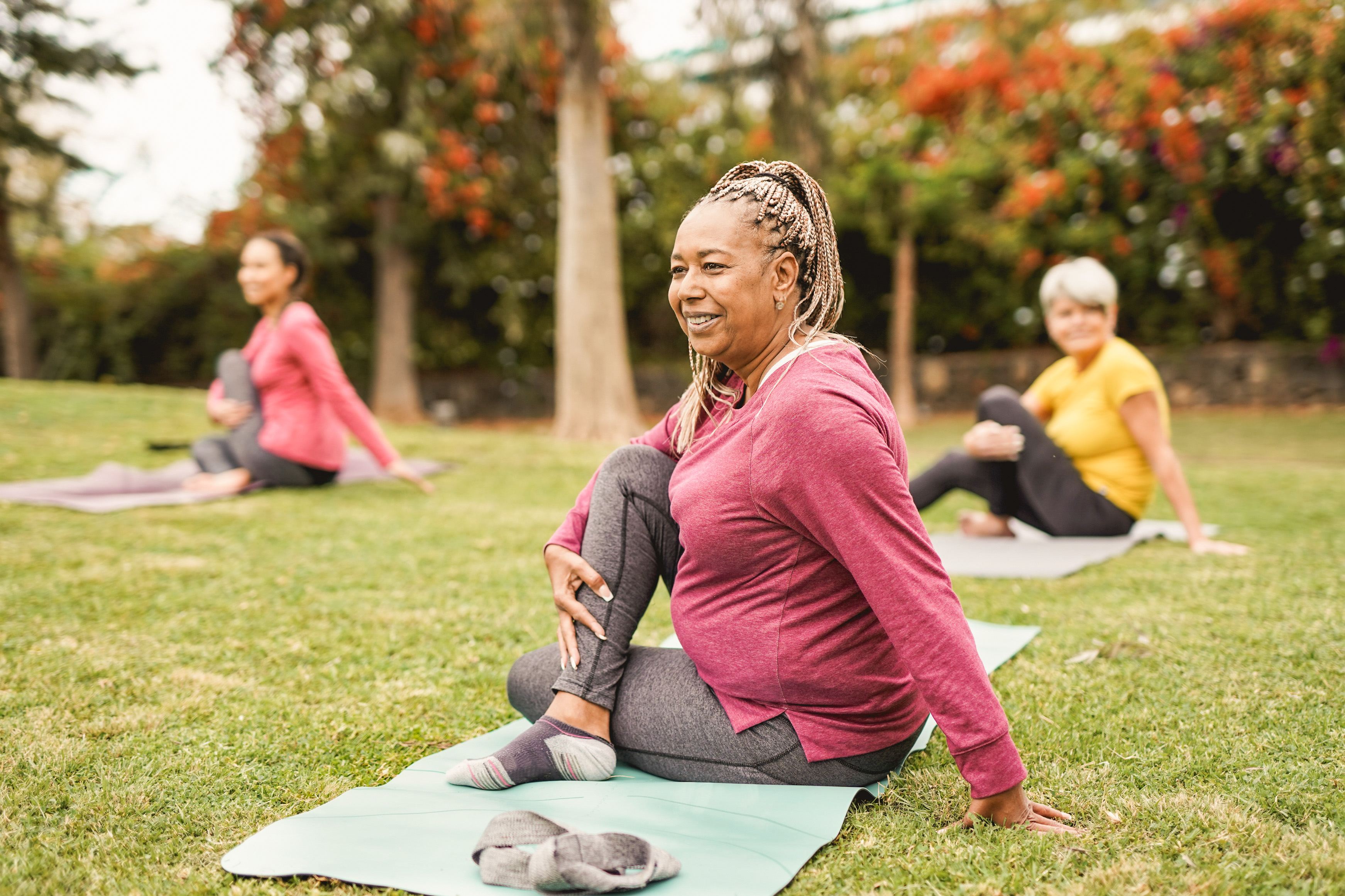 An outdoor yoga class showing people of diverse genders and skin tones.